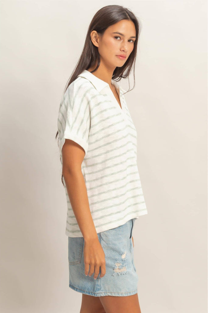 Woman wearing a striped shirt and denim shorts against a plain background