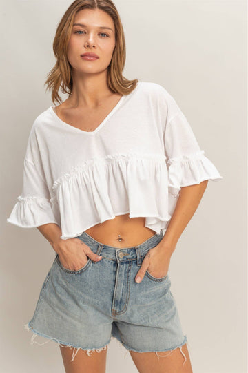 Woman wearing a white blouse and denim shorts on a plain background