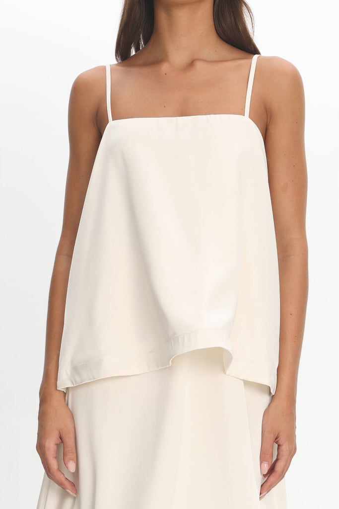 Woman wearing a white sleeveless top and pants on a white background